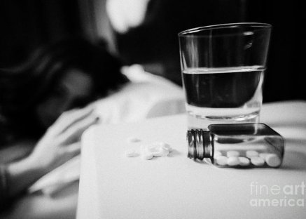 glass-of-water-and-bottles-of-sleeping-pills-on-bedside-table-of-early-twenties-woman-in-bed-in-a-be-joe-fox.jpg